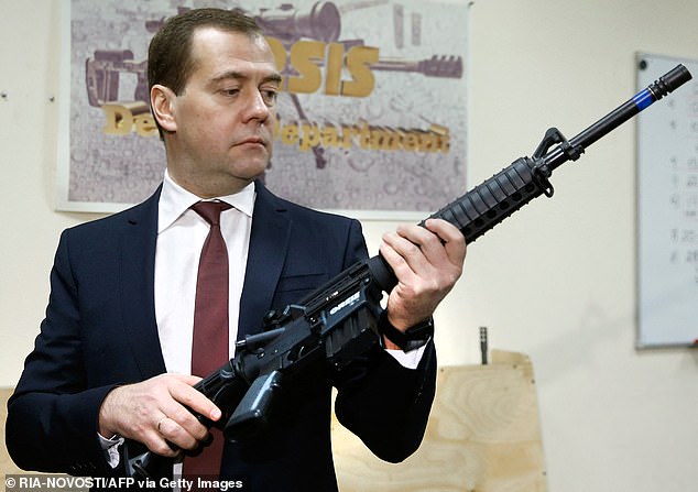 FILE: Russian Prime Minister Dmitry Medvedev holds a Russian-made Orsis gun during a visit to the Promtechnologiya firearms company in Moscow, Nov. 19, 2013.