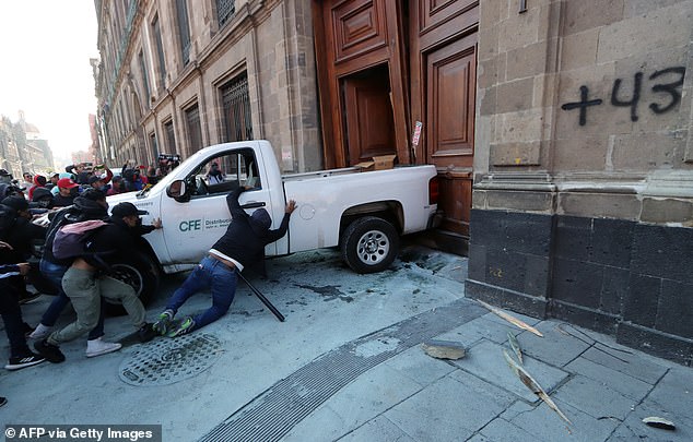 Protesters push a van to break down a door at the National Palace, the home of Mexican President Andrés Manuel López Obrador, in Mexico City on Wednesday.