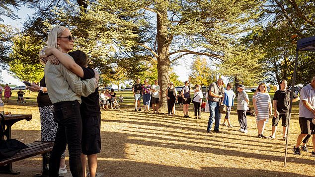 A child holds his mother as mourners line up to pay their respects to Samantha Murphy in Ballarat Victoria.