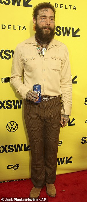 Post Malone drank a can of Bud Light while wearing a beige button-down shirt and brown patterned pants at the premiere.
