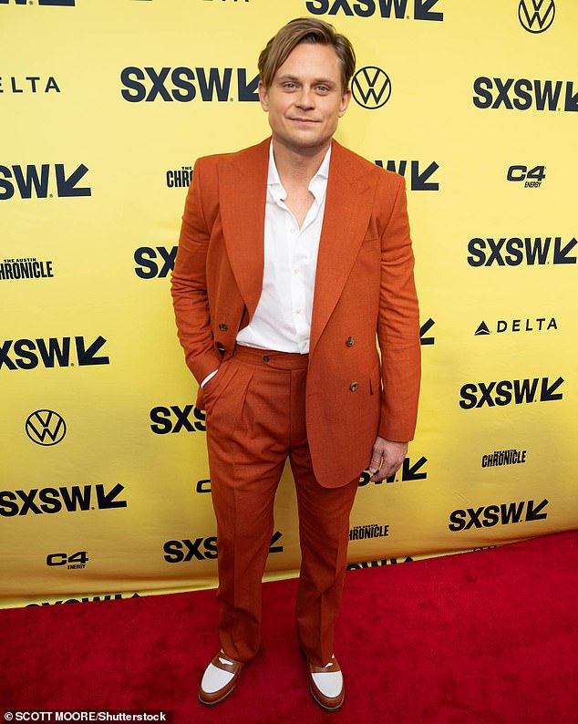 Billy Magnussen stood out in a dark orange double-breasted jacket and two-tone shoes that perfectly matched the tones of his clothing.
