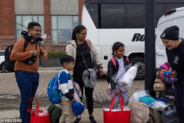 Alejandra Pérez, her ex-partner Jader Castro and their children Sharlott Barrios, 9, and Juan Sebastián Castro, 5, all Colombian asylum seekers, are greeted by a volunteer after arriving by bus in Chicago from Texas, in downtown Chicago, Illinois. United States, October 25, 2023