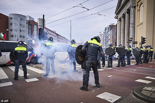 Demonstrators set off some fireworks as Dutch riot police form a line during a protest against Israeli President Isaac Herzog attending