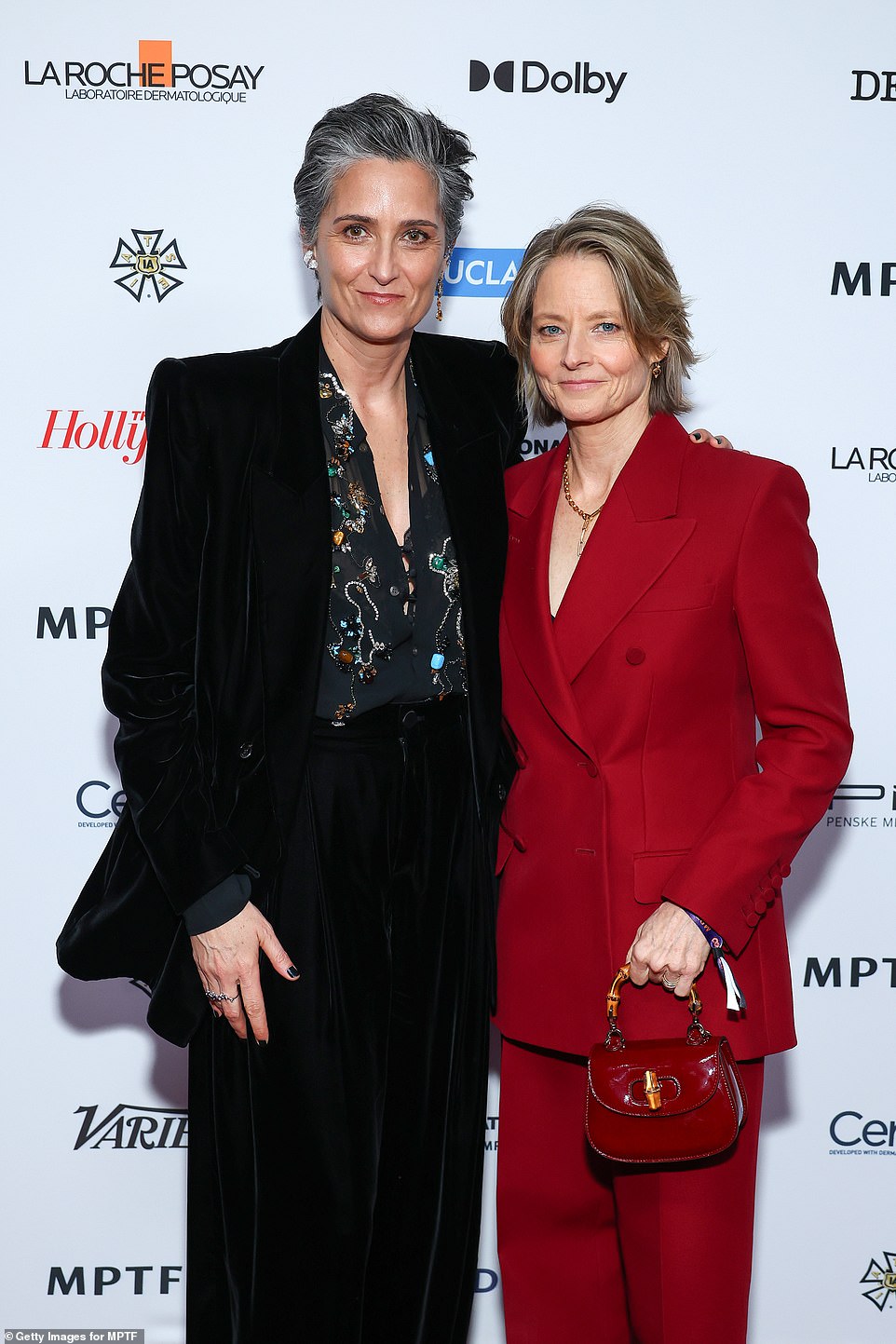 Jodie Foster wore a red suit as she clutched a small red handbag as she posed with partner Alexandra Hedison, who opted for a black outfit with black nails