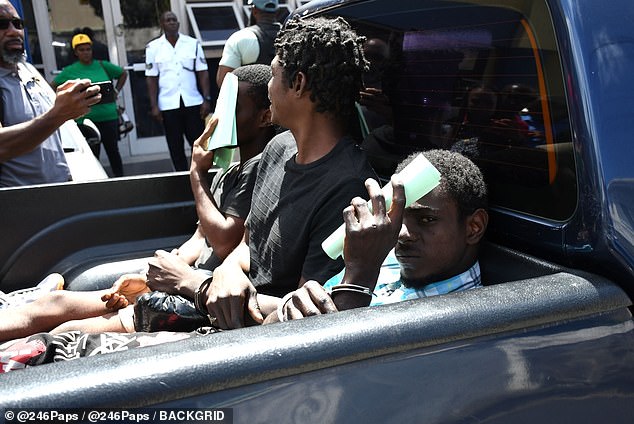 Two of the three murder suspects are seen hiding their faces with paper in the back of a pickup after they left court.  The person in the middle is another prisoner being transported, unrelated to the case