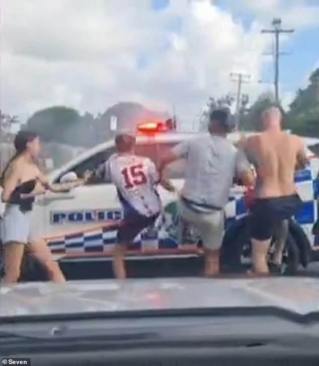 Queensland Police are still investigating the incident itself, which saw three police cars damaged (pictured, participants kicking a police car)