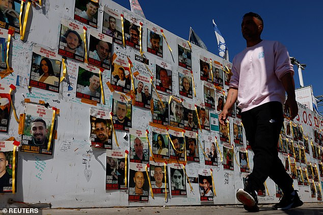 A man walks past posters with pictures of hostages kidnapped in the deadly October 7 attack on Israel by the Palestinian Islamist group Hamas from Gaza in Tel Aviv, Israel