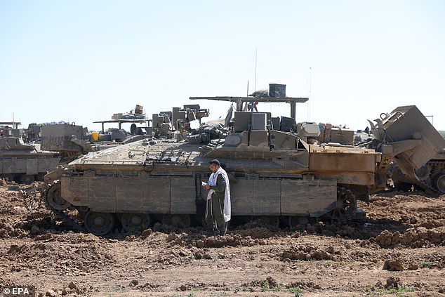 Israeli soldiers pray in front of an armored fighting vehicle in an area near the border with the Gaza Strip at an undisclosed location in southern Israel
