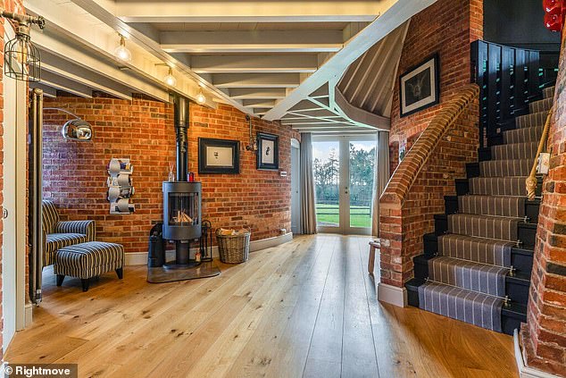 This living space includes wooden floors, a wood stove and exposed brick around a staircase.