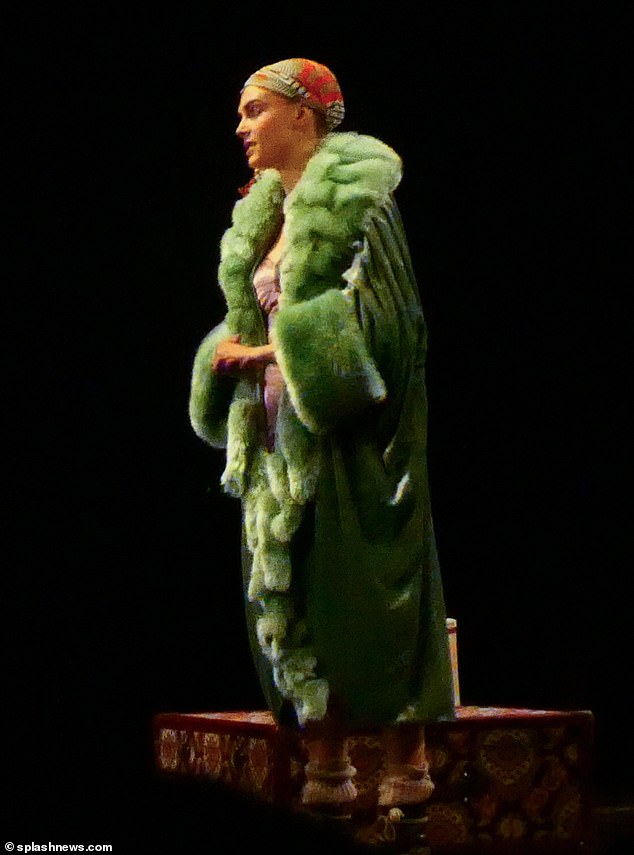 Another scene saw Cara dressed in an elaborate green fur coat and patterned headscarf