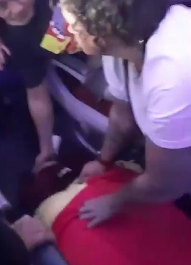 A passenger on board flight LA800 is pictured being treated on the floor of the plane on Monday
