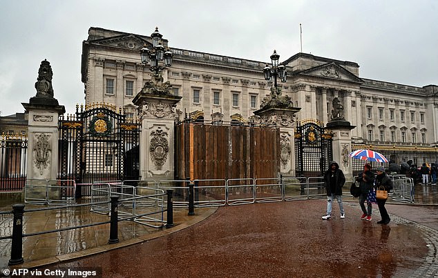 People walk past the decorated gates outside Buckingham Palace in London on Sunday