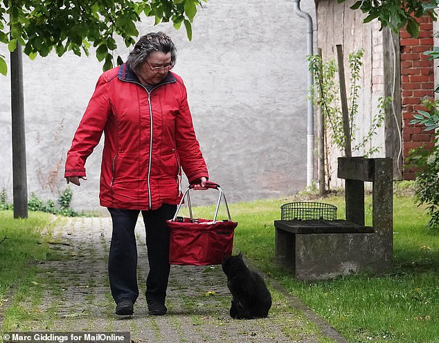 Mrs. Brueckner is shown feeding a cat in the park in Bergtheim, Bavaria, 2020.