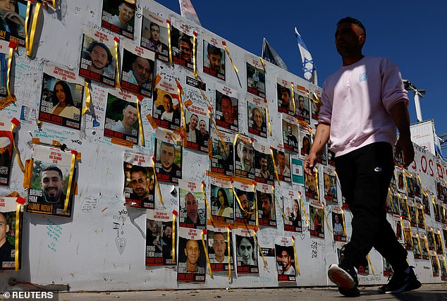 A man walks past posters with pictures of hostages kidnapped in the deadly October 7 attack on Israel by the Palestinian Islamist group Hamas from Gaza in Tel Aviv, Israel