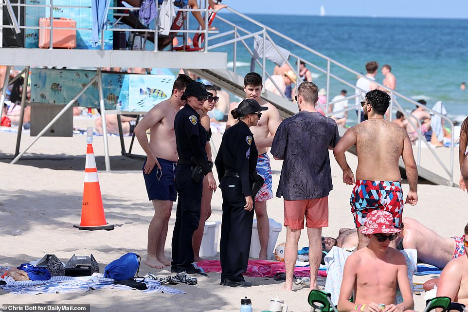 Local officers can be seen in this photo talking to a group of revelers on the beach on Tuesday, it is unclear what