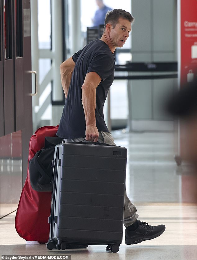 The athlete had a large black hand luggage in one hand and a red garment bag in the other