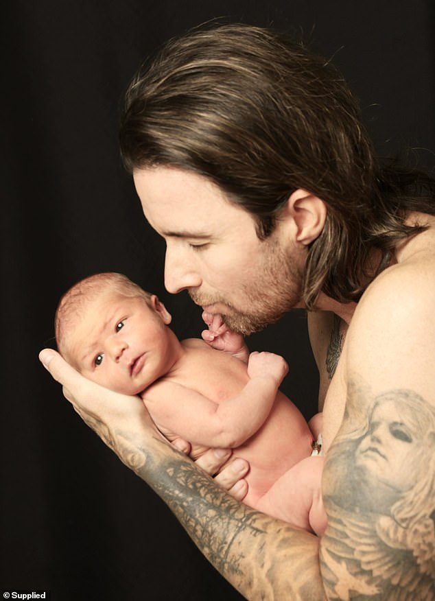 In the first photo, Michael is seen cradling the cute newborn in his muscular, well-tanned arms. Pictured