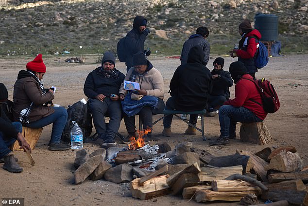 Migrants sit by a campfire in California, waiting for US Border Patrol officials to pick them up