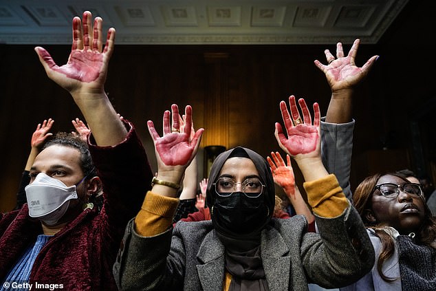 Protesters calling for a ceasefire in Gaza raise their hands, painted in red, during a Senate Appropriations Committee hearing with US Secretary of State Antony Blinken and US Defense Secretary Lloyd Austin on October 31, 2023 in Washington, DC