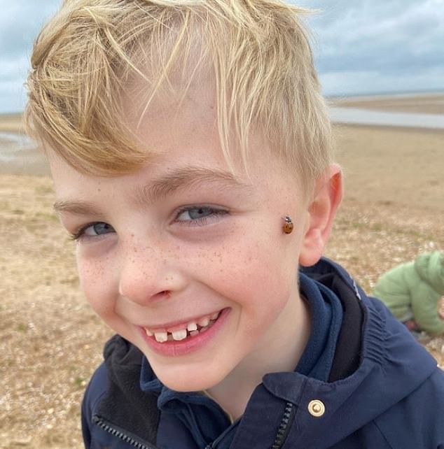 Nine-year-old Arthur is pictured with a ladybug on his cheek while doing one of his climbs.