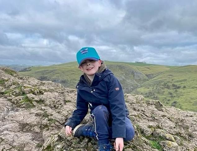 Arthur smiles as he sits on top of Thorpe Cloud in the Peak District