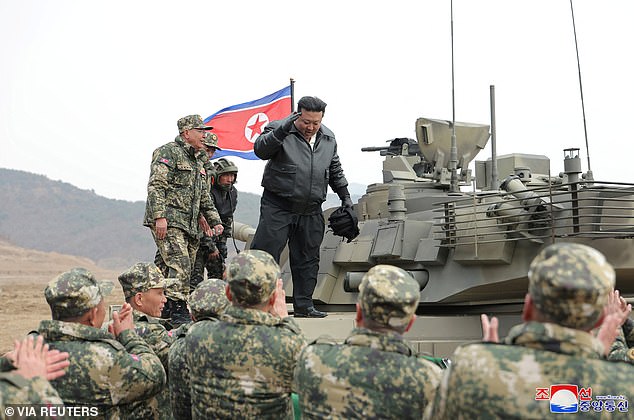 Kim Jong Un (pictured) stood on top of a tank as he addresses troops