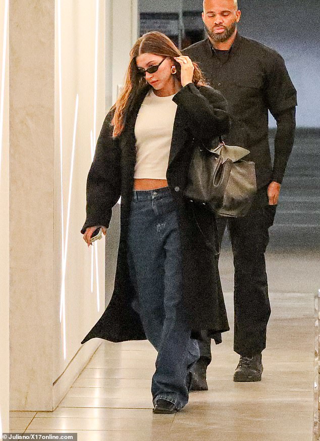 She looked stylish in a cropped white T-shirt, a black trench coat and jeans