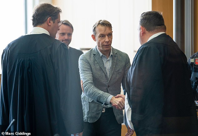 Dressed in his trademark creased gray suit, which he has worn to all the previous hearings, he shook hands and smiled with his legal team as he was led into court
