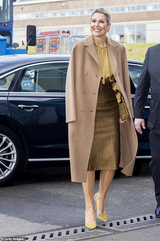She wore a medium length camel coat over a fitted gold jacquard pencil skirt and matching silk top