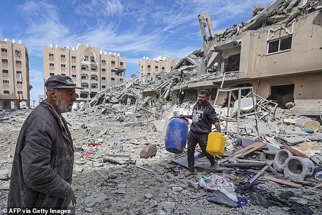 A displaced Palestinian man carries containers among the rubble of houses destroyed by Israeli bombardment in the Hamad area, west of Khan Yunis in the southern Gaza Strip on March 14, 2024