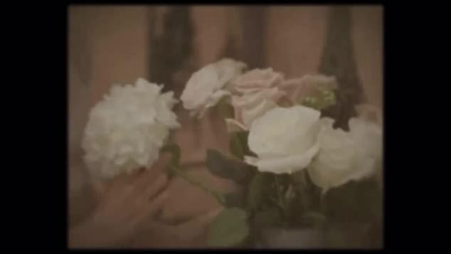 The video starts with a washed out video of a woman arranging white and pink pastel flowers