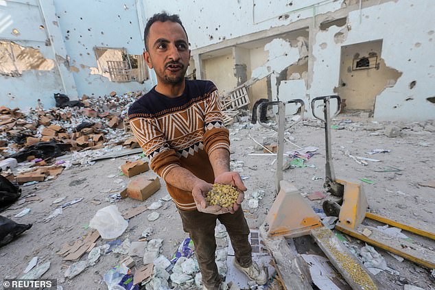 A Palestinian holds pieces of pasta at the site of an Israeli attack on an aid depot amid the ongoing conflict between Israel and Hamas