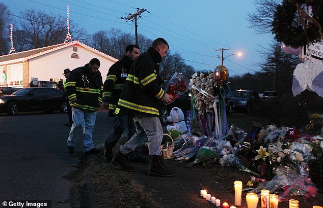 Firefighters walk to pay their respects at a makeshift memorial near the school after the mass shooting at Sandy Hook Elementary School on December 15, 2012