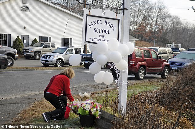 A woman places flowers at the Sandy Hook Elementary School sign on December 15, 2012