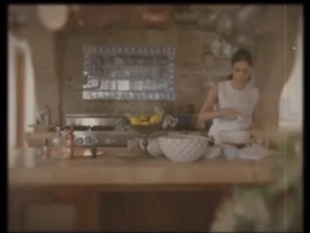 It then fades to reveal Meghan cooking in a stunning kitchen with copper pots hanging over her head as she whips