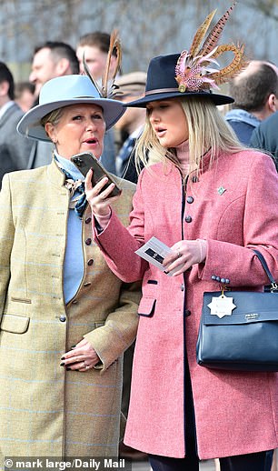Two spectators choose feathered fedoras to keep the rain away