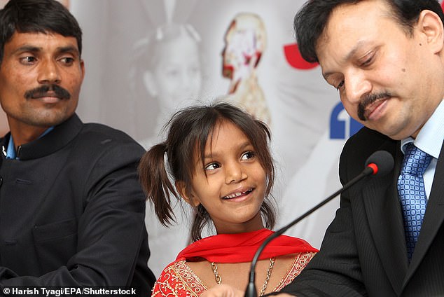 Pinki Sonkar shows her famous smile to Dr Subodh Kumar Singh (right), who operated on her cleft palate, while her father Rajendera Sonker looks on (left)