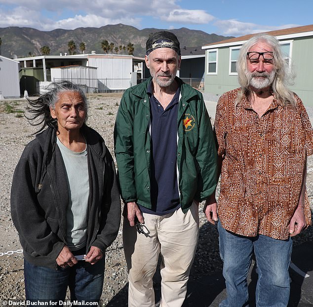 Friends Norma Teyechea, 74, Dan Berlin, 62, and Robert Berlin, 61, stand in front of the lot where Bernard's trailer burned down in 2015
