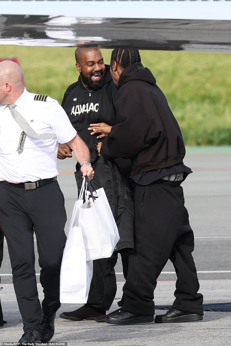 Kanye burst out laughing with a pal on the tarmac and appeared to be in a jovial mood