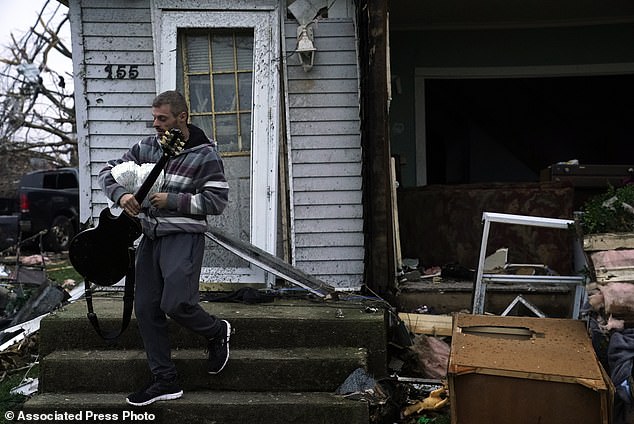 Blaine Schmidt holds his guitar near his damaged home after a severe storm Friday, March 15, 2024, in Lakeview, Ohio.  (AP Photo/Joshua A. Bickel)