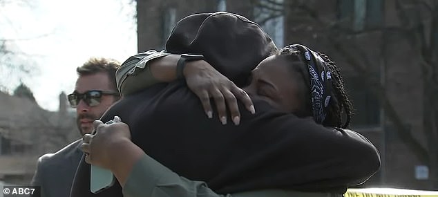 Pictured: Neighbors embrace each other as they mourn the death of Jayden Perkins