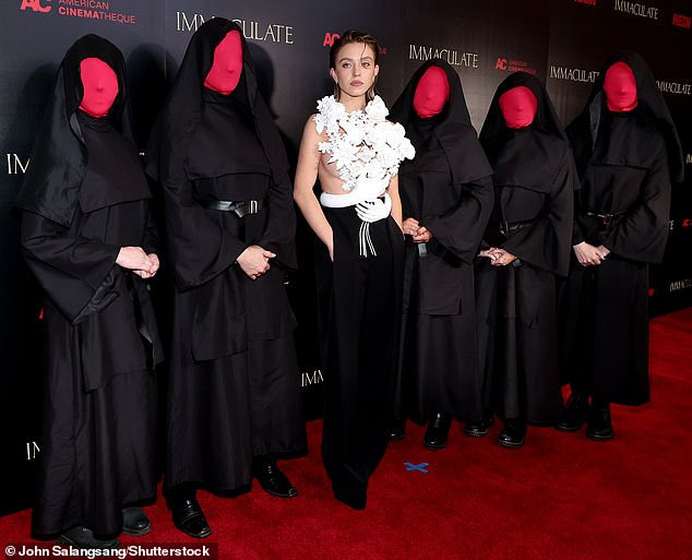 Sydney proudly showed off her natural look with complementary make-up accented with heavy mascara and a glossy nude lip as she posed with models dressed as nuns with their faces covered