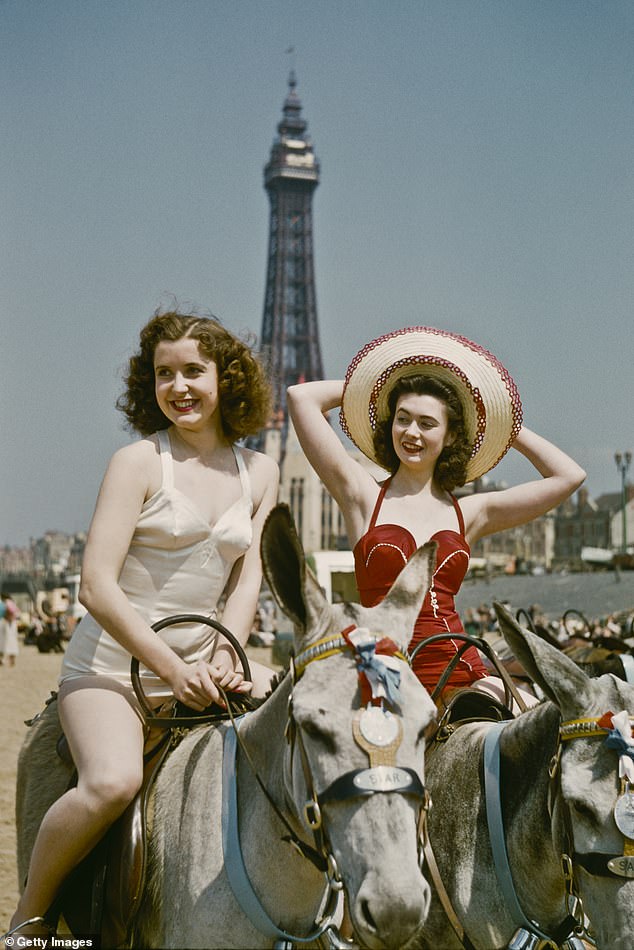Holidaymakers riding donkeys on the beach at Blackpool in July 1954