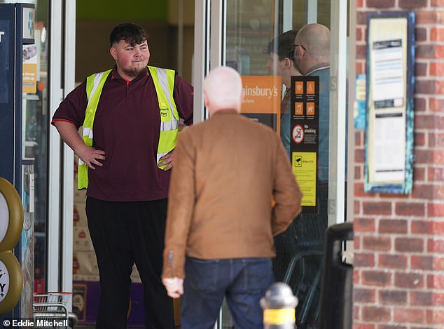 An apparent security worker stands guard outside the Sainsbury's store in Lyons Farm, Worthington this morning.