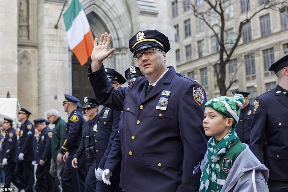 A New York police officer waves to the crowd during the St Patrick's Day Parade in New York