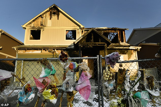 Old bouquets, stuffed animals and other memorabilia hang on the fence around the family's burnt down home