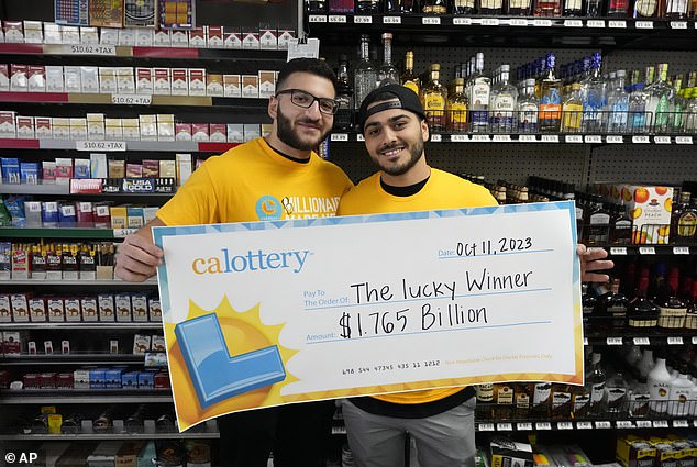 Jonathan Khalil, left, and Chris Khalil, sons of store co-owners, hold up a ceremonial check after the winning $1.765 billion Powerball ticket was sold
