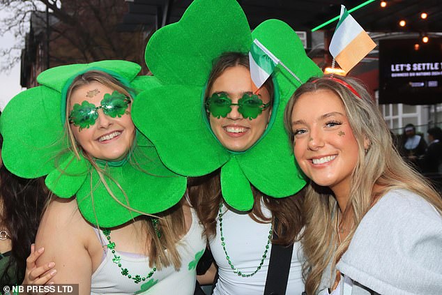 Pictured: Revelers wearing shamrock-style headdresses and Irish flags on the eve of All Saints' Day