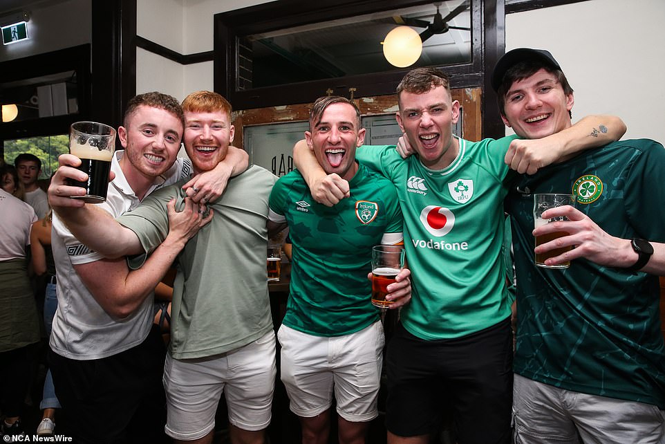 A group of young men proudly raise a glass to Ireland