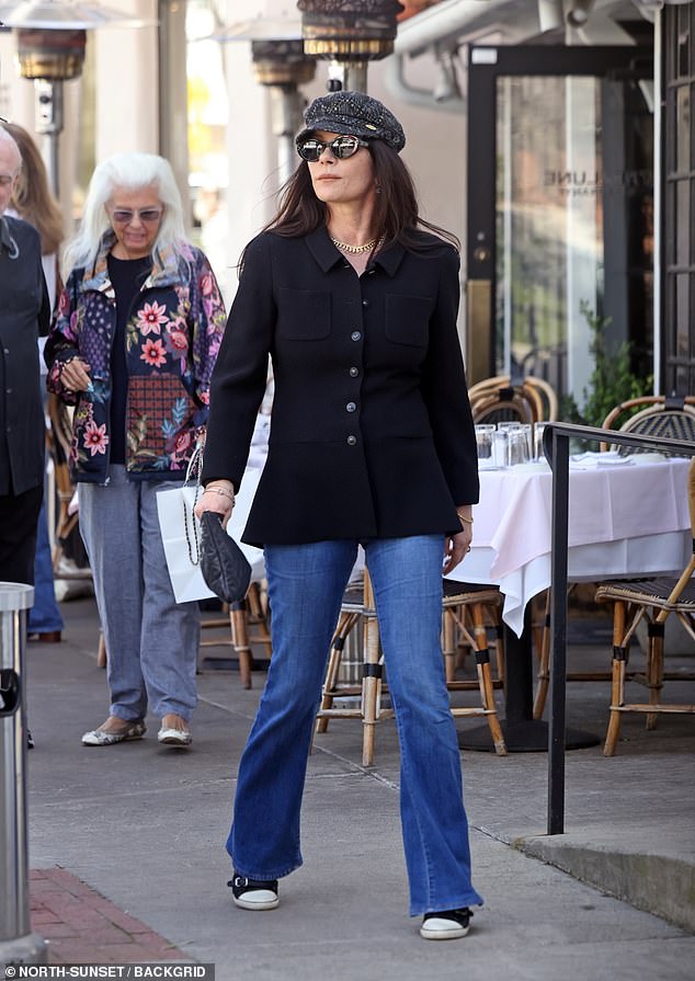 The Wednesday actress, 54, cut a stylish figure in a long black shirt, which she teamed with blue denim jeans, black sneakers and a coordinating Chanel bag